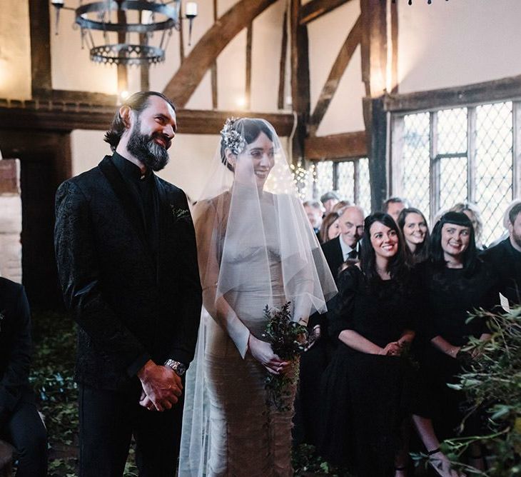 Bride and groom tie the knot at intimate gothic wedding ceremony with foliage decor