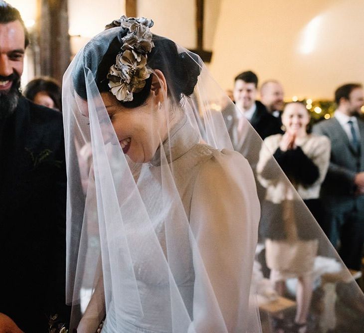 Bride wearing vintage styled floral headpiece with corset waist dress and groom in black suit