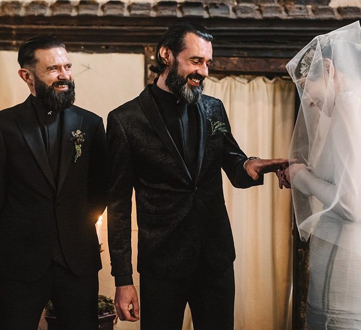 Bride wearing vintage styled floral headpiece with corset waist dress and groom in black suit tie the knot