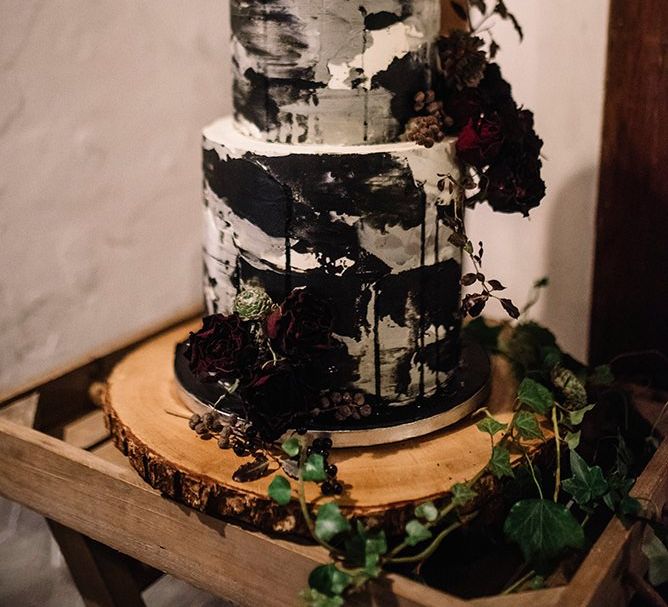 Cake at Gothic wedding with floral detailing on tree stump stand