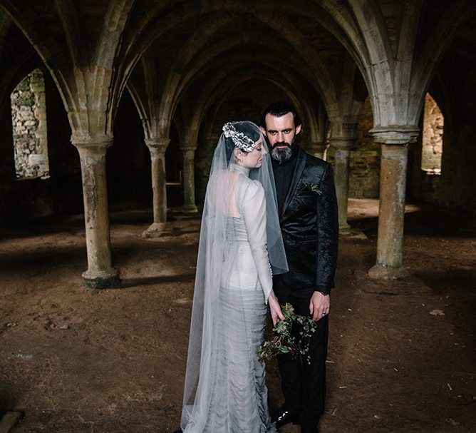 Bride wearing silver gothic styled dress with corset waist, cob-web train and foliage bouquet