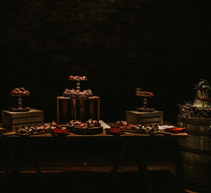 Two-Tier Drip Wedding Cake Decorate with White Flowers and Green Foliage, Displayed on Beer Barrel | Rustic Dessert Table | Festoon Light Canopy and Indoor Trees for Humanist Wedding in St Andrews | Carla Blain Photography