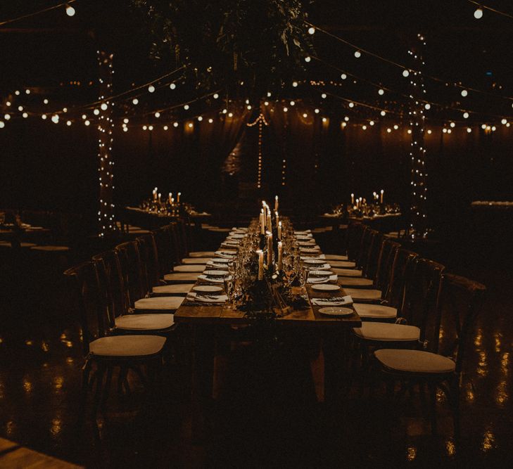 Wooden Banquet Tables | Foliage Table Runners | White Tapered Candles | Rosemary Sprig Place Setting | Kinkell Byre Wedding Venue | Festoon Light Canopy and Indoor Trees for Humanist Wedding in St Andrews | Carla Blain Photography