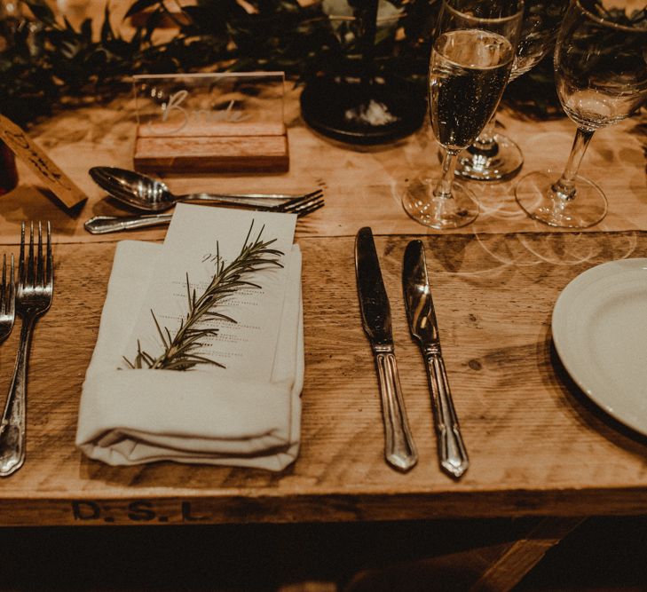 Rosemary Sprig Place Setting | Perspex Name Setting | Alcohol Favour with Drink Me Tag | Wooden Banquet Table | Foliage Table Runner | Kinkell Byre Wedding Venue | Festoon Light Canopy and Indoor Trees for Humanist Wedding in St Andrews | Carla Blain Photography