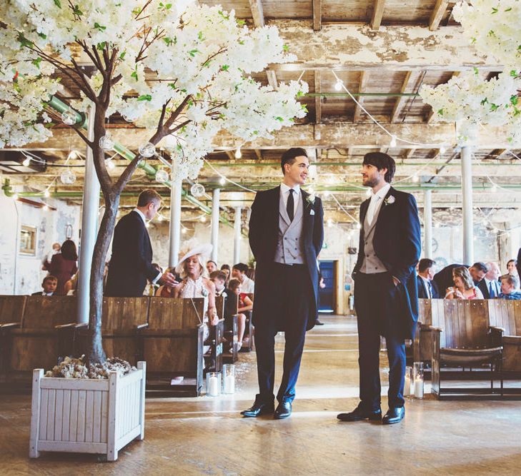 Groom and Best Man Waiting at Altar | Groom in Navy Tails and Grey Waistcoat | Cherry Blossom Tree Altar | Festoon Lights | Lace Bridal Cape Veil &amp; Fishtail Wedding Dress by Pronovias | On Love and Photography