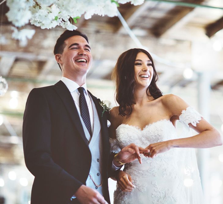 Wedding Ceremony | Bride in Fishtail Pronovias Wedding Dress with Off Shoulder Sleeves and Veil Cape | Groom in Navy Tails and Grey Waistcoat | Bride Wearing Hair Down | Cherry Blossom Tree Altar | Lace Bridal Cape Veil &amp; Fishtail Wedding Dress by Pronovias | On Love and Photography