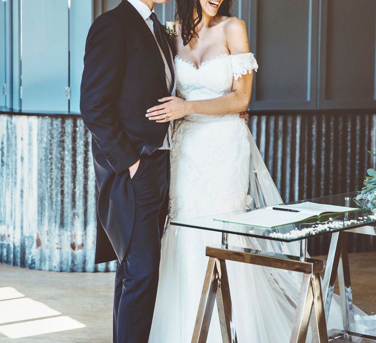 Signing of Register | Bride in Fishtail Pronovias Wedding Dress with Off Shoulder Sleeves and Veil Cape | Groom in Navy Tails and Grey Waistcoat | Bride Wearing Hair Down | Lace Bridal Cape Veil &amp; Fishtail Wedding Dress by Pronovias | On Love and Photography