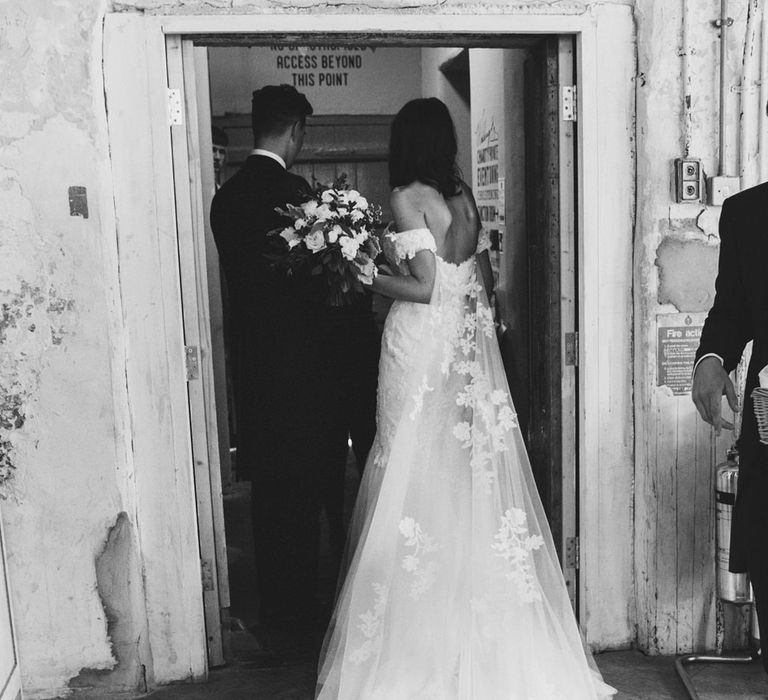 Bride in Embroidered Pronovias Wedding Dress with Off Shoulder Sleeves and Veil Cape | Groom in Navy Tails and Grey Waistcoat | Bride Wearing Hair Down | Bridal Bouquet of White Roses and Greenery | Lace Bridal Cape Veil &amp; Fishtail Wedding Dress by Pronovias | On Love and Photography