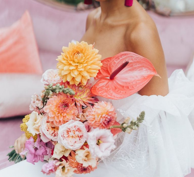 Bride holding a blush pink, peach and coral wedding bouquet with dahlias and anthuriums  at Chiddingstone Castle