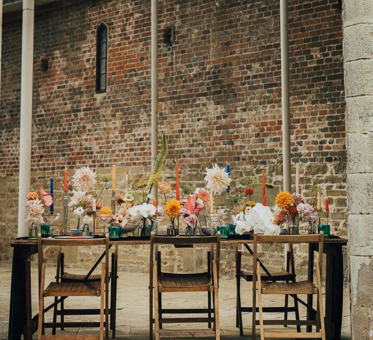 Outdoor table decor at Chiddingstone Castle with colourful flowers and candles