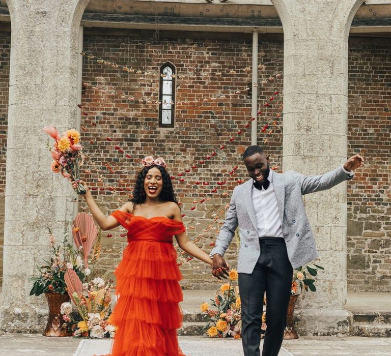 Bride in red tulle wedding dress and groom in Grey jacket and bow tie at Chiddingstone Castle