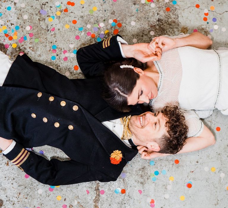 Bride and groom laying on the floor of Boat shed for colourful wedding theme