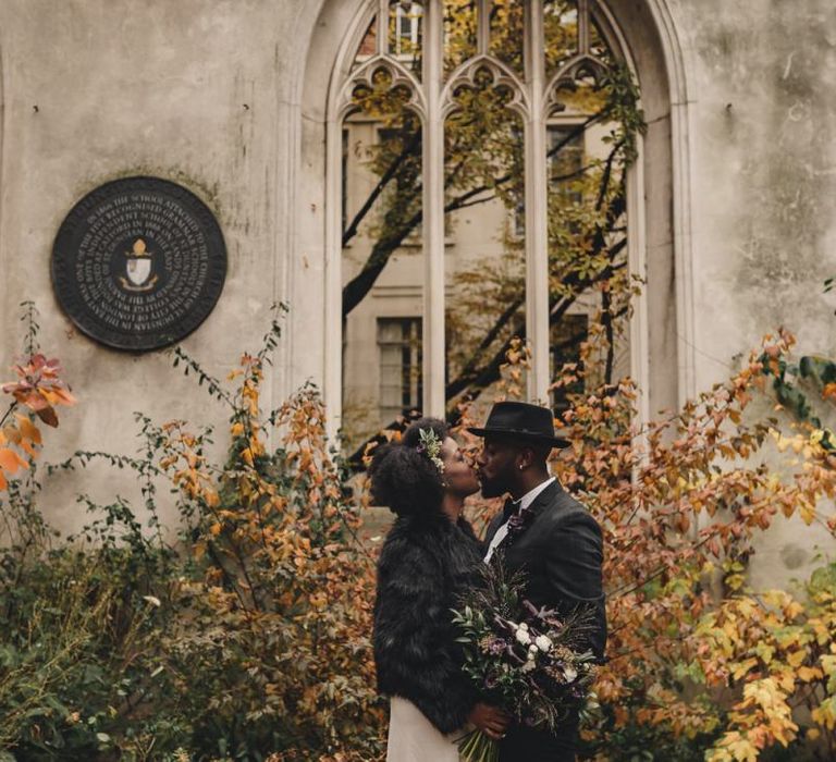 Bride and groom kissing in St Dunstan in the East gardens