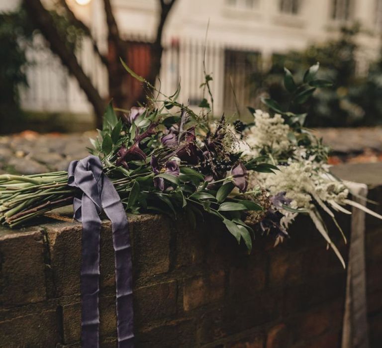 White and purple wedding bouquets with foliage tied with ribbon