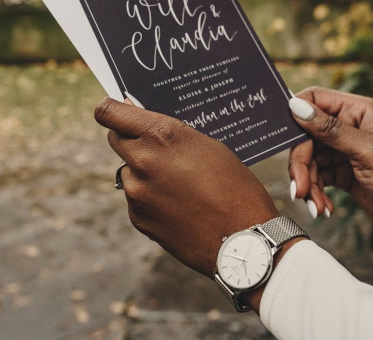 Bride holding a black and white wedding invitation  with white nail polish