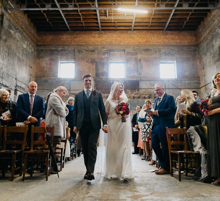 Bride and groom walking down the aisle together at the Asylum Chapel in London