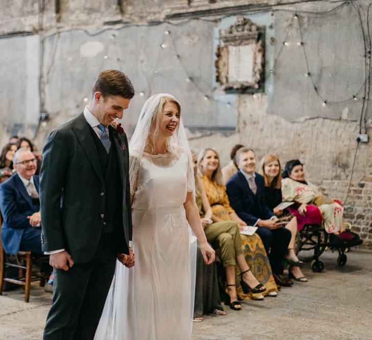 Bride wearing a sophisticated dress with lace tipped veil with her groom at London wedding