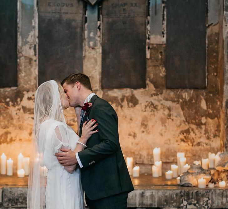 Bride and  grooms first kiss with candle light backdrop