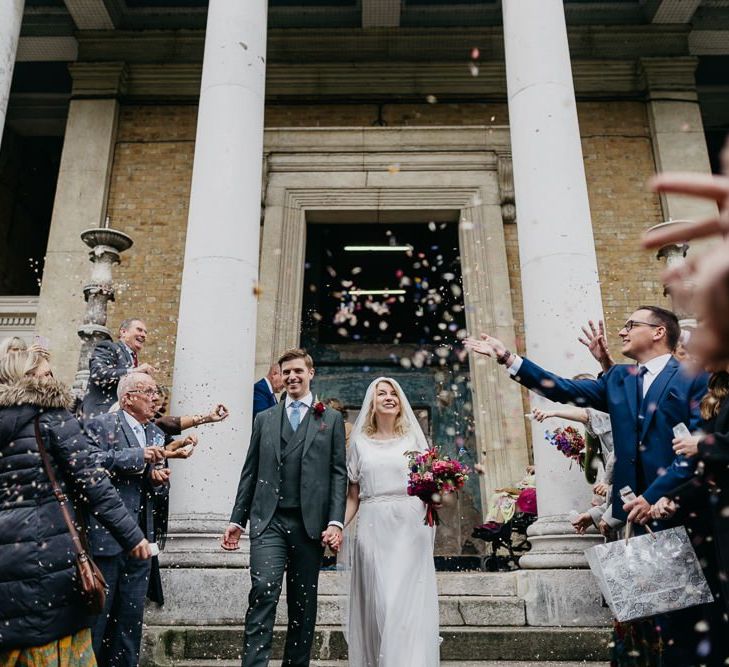 Bride and groom confetti shot as they tie the knot at city celebration in London with pine cone wedding decor