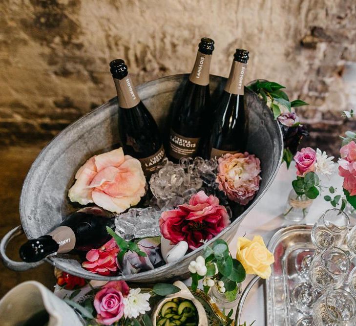 Drinks table at colourful and fun reception in London with floral and pine cone wedding decor