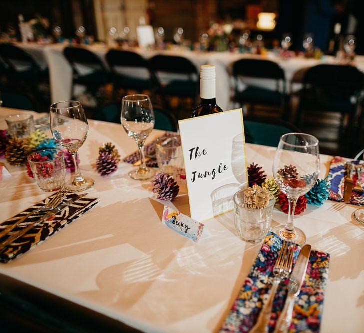 Reception styling for colourful, fun and eclectic day with pine cone wedding decor and hand painted placecards