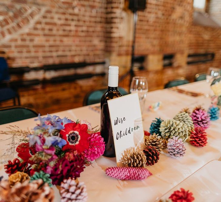 Styling for colourful and eclectic day with pine cone wedding decor and bright floral centrepieces