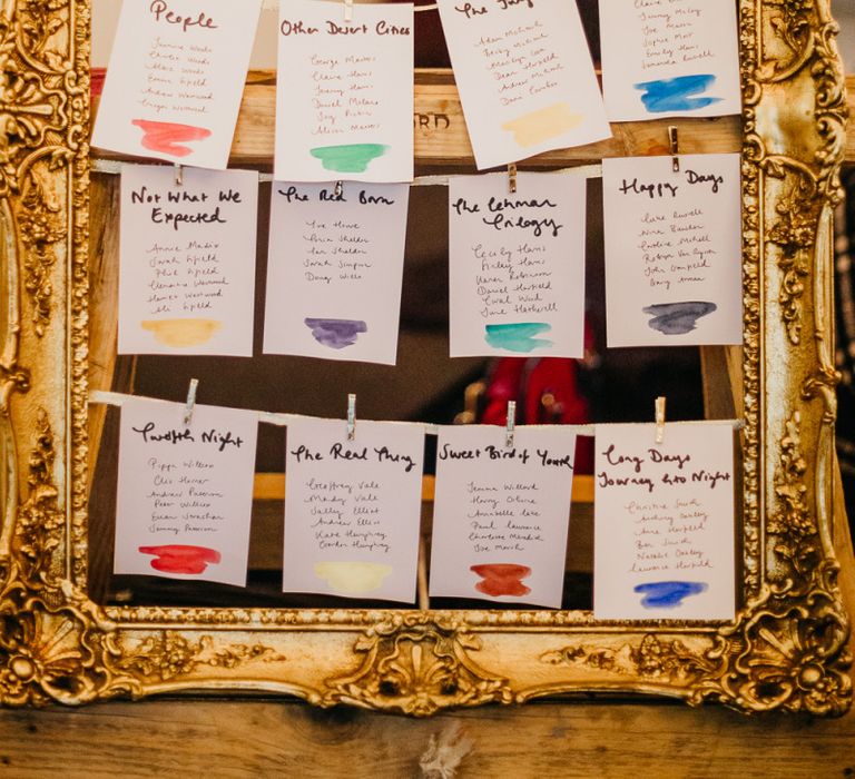 Mirror table plan with handmade colourful signs and pine cone wedding decor