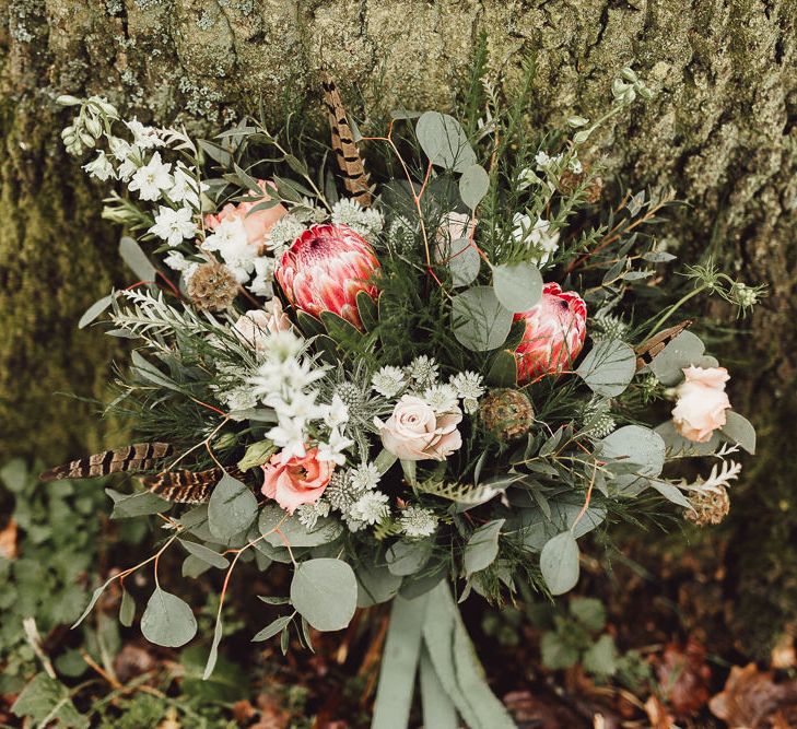 Foliage, Coral Flowers &amp; Pheasant Feather Bouquet with Proteas | Country Boho Inspiration in the Woodlands of Happy Valley Norfolk | Cara Zagni Photography