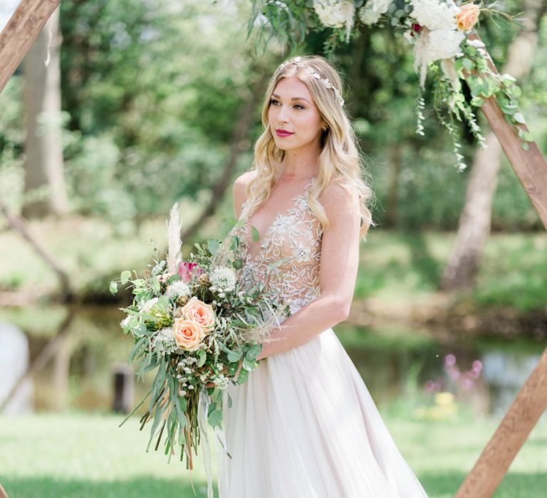 Beautiful Bride in Watters Wedding Dress Holding a Foliage and Peach Rose Wedding Bouquet