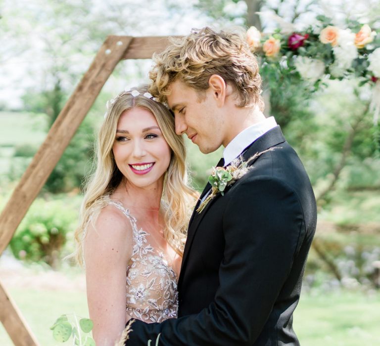 Smiling Bride in Watters Wedding Dress and Groom in Black Suit Standing at the Hexagonal Altar