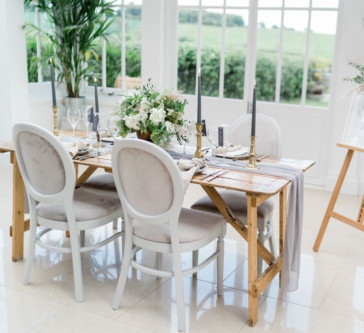 Wooden Tablescape with Grey Linen Table Runner, Gold Candlesticks and Dark Grey Taper Candles