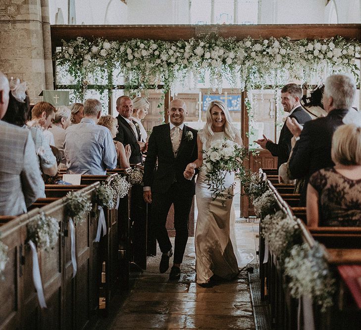 Bride and Groom Exiting the Church Wedding Ceremony with White and Green Wedding Flower Decor