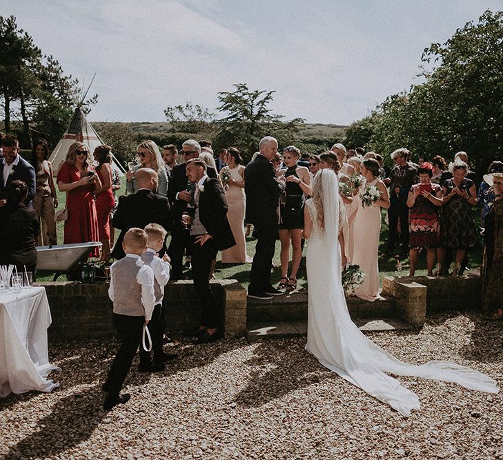 Bride in St Patrick Wedding Dress and Cathedral Veil Enjoying Drinks Reception at East Afton Farmhouse