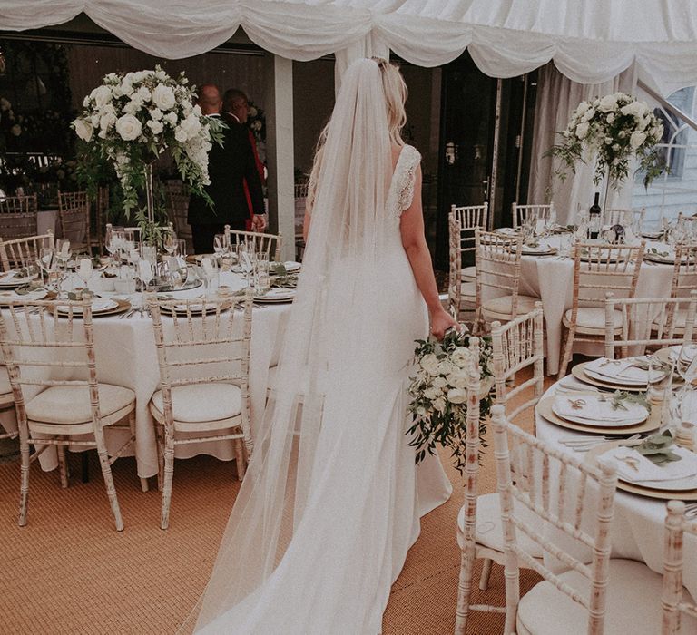 Bride in St Patrick Wedding Dress and Cathedral Length Veil Walking Through Marquee Wedding Reception