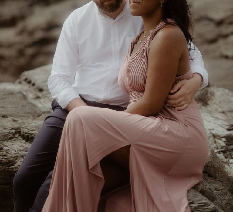 bride and groom sitting on the rocks at Godrevy beach in Cornwall