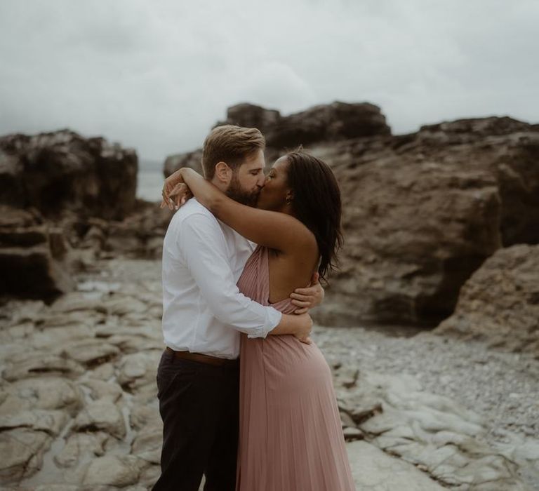 Bride and groom to be kissing on the rocks in Cornwall