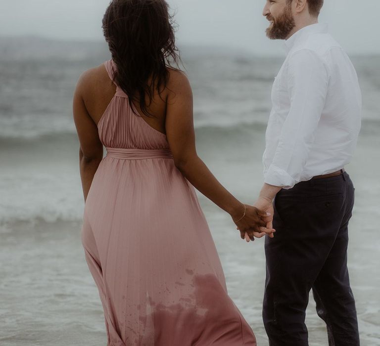 Bride and groom to be holding hands on the beach