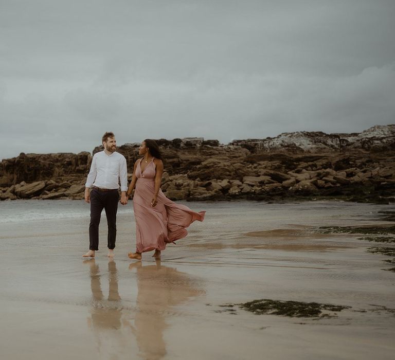 Bride and groom walking through the surf on the beach