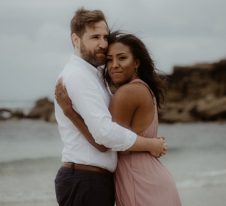 Bride and groom to be embracing on the beach in Cornwall