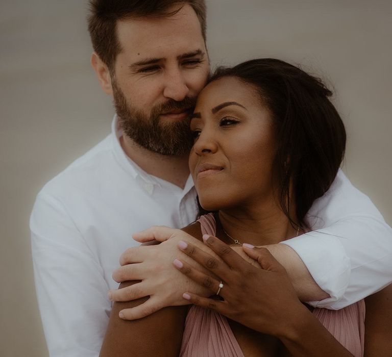 Groom in white shirt embracing his bride-to-be during their engagement session