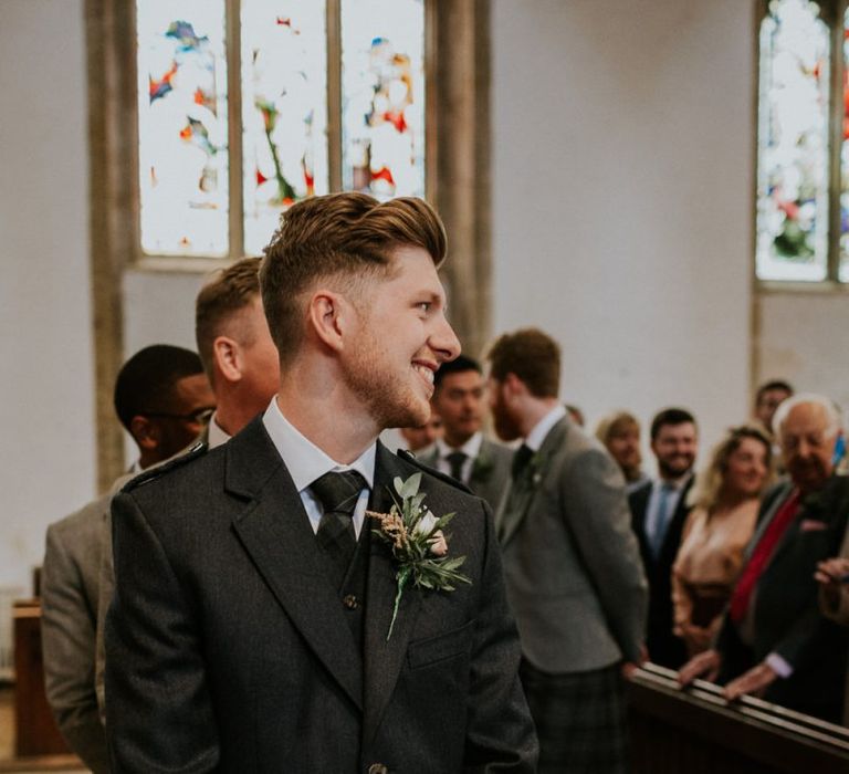 Groom in kilt waits for bride in Enzoani wedding dress