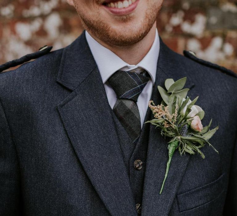 Groom in kilt with floral buttonhole and thistle