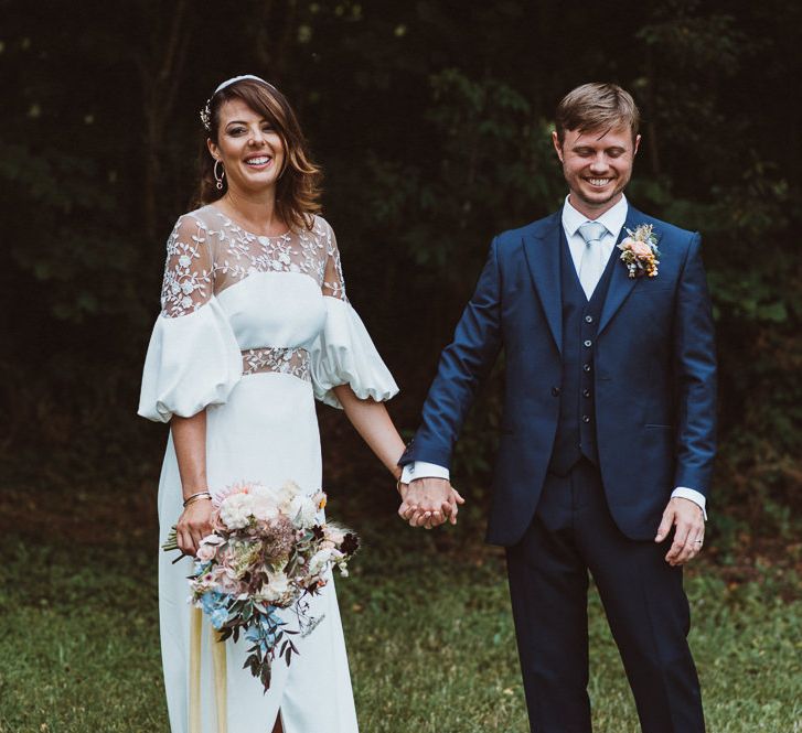 Bride in Rime Arodaky Wedding Dress and Groom is Reiss Suit Holding Hands