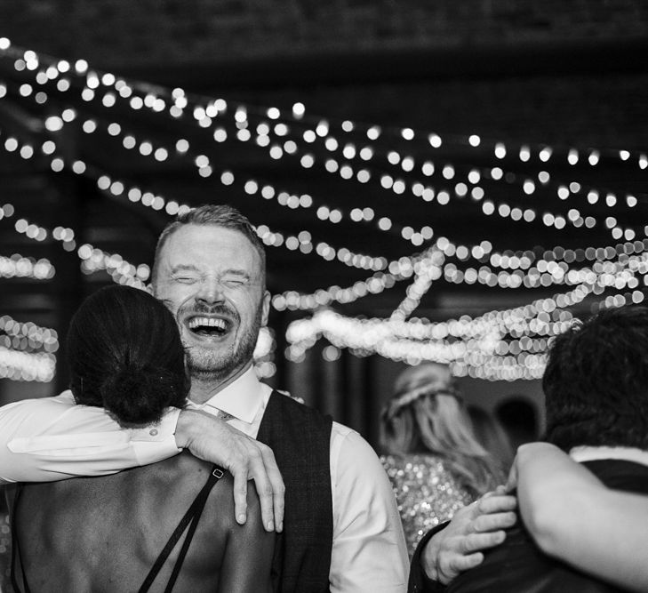 Groom Hugging Wedding Guests on the Fairy Light Covered Dance Floor