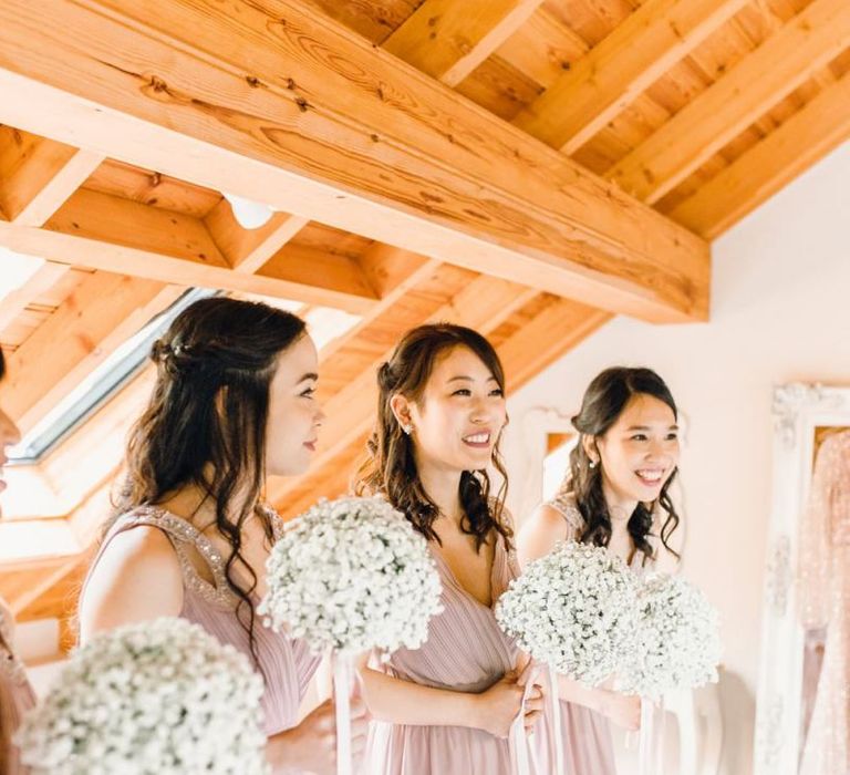 Bridesmaids in dusky pink dresses for traditional celebration with gypsophila bouquets