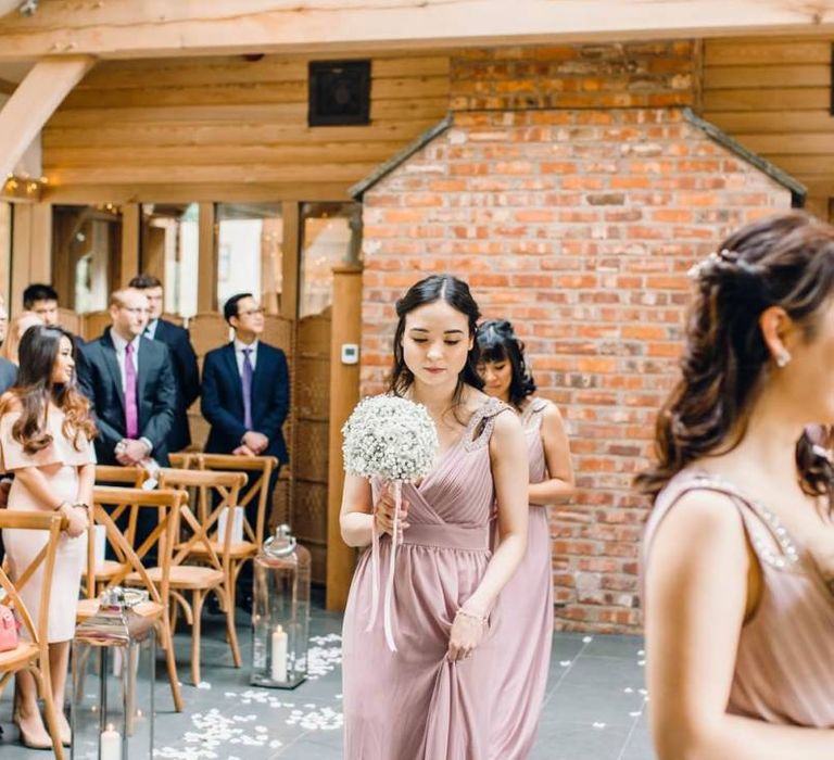 Bridesmaids in dusky pink dresses for traditional celebration with gypsophila bouquets