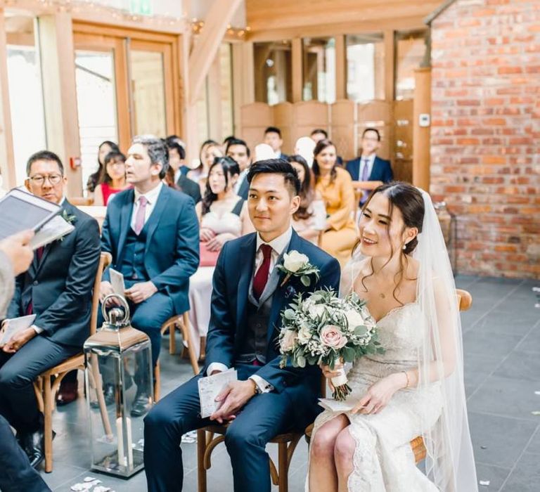 Bride and groom take a seat at this traditional ceremony with rustic detailing