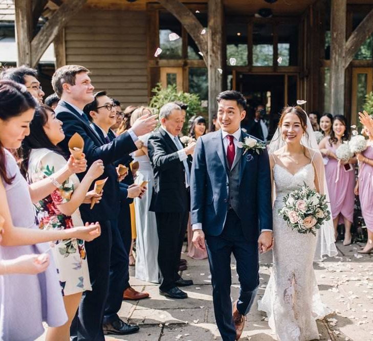 Bride wearing a lace dress and groom in a three piece suit leaving the wedding ceremony