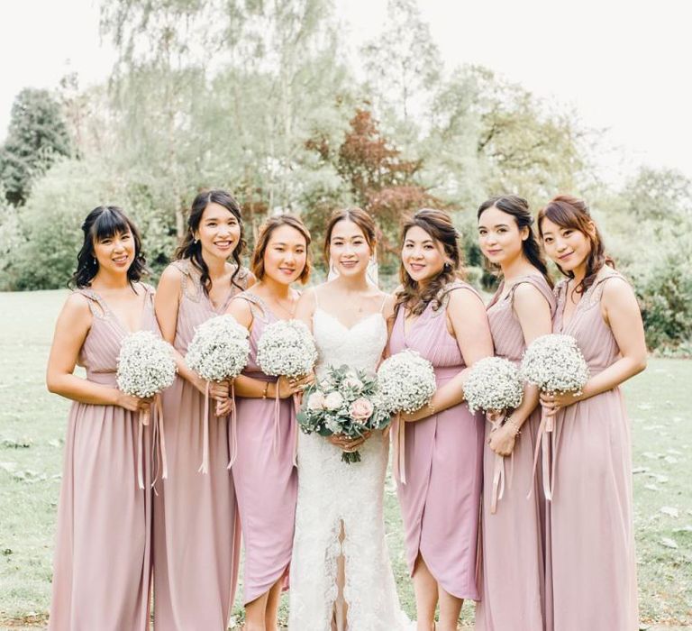 Bridesmaids in dusky pink dresses for traditional celebration with gypsophila bouquets