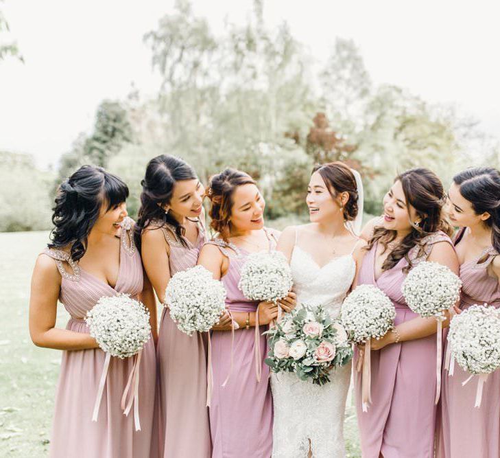 Bridesmaids in dusky pink dresses for traditional celebration with gypsophila bouquets